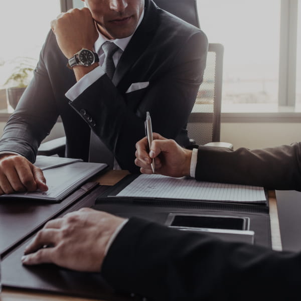 Business people in suits signing an important contract at a desk.