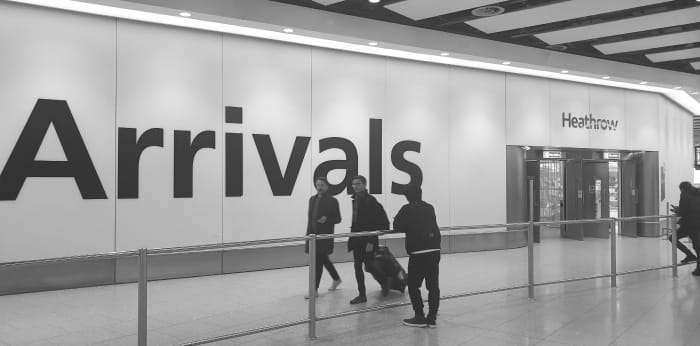 Concierge waiting for clients at airport arrival gate as people exit.