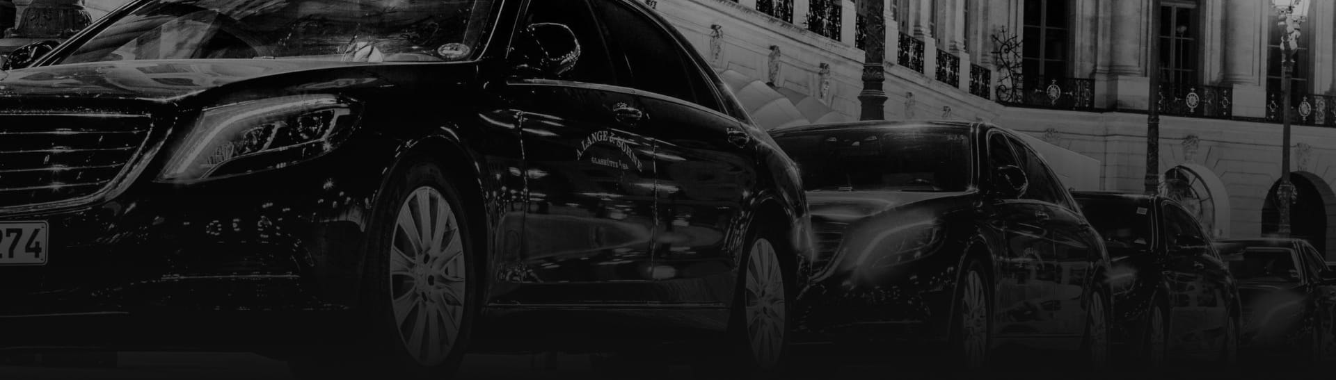 Luxury Black Sedans Lined Up in Front of a Luxury Hotel.